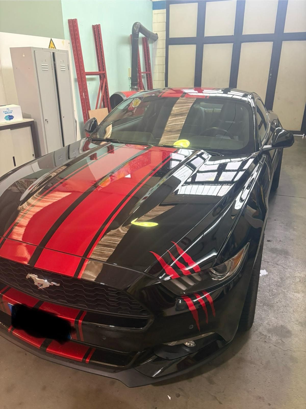 Ford Mustang nera con strisce rosse racing e dettagli grafici in pellicola
