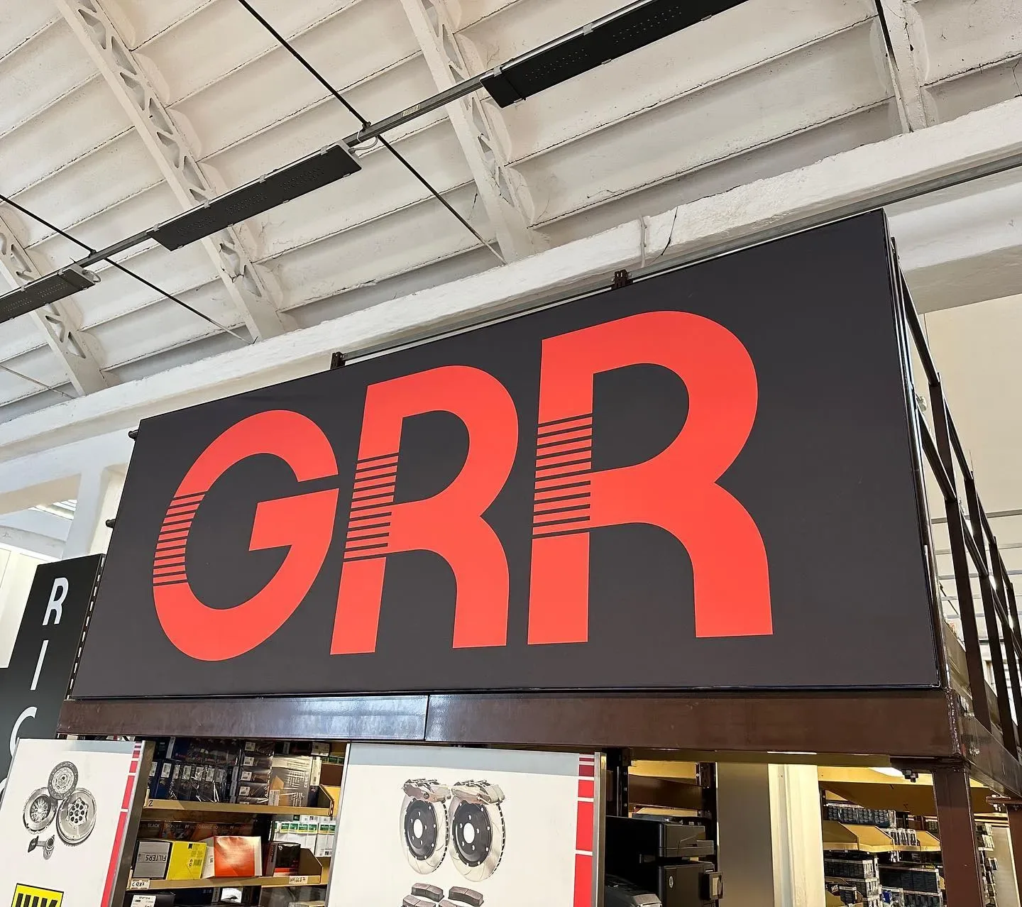Insegna interna con logo GRR rosso su pannello nero sopra il bancone ricambi